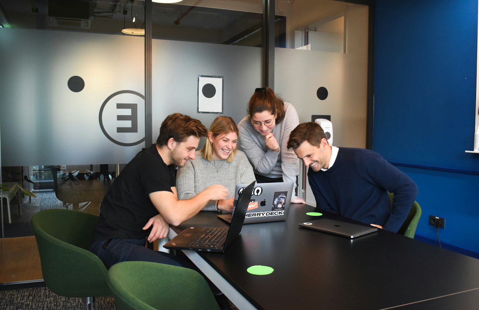 Vier Kollegen schauen gemeinsam auf einen Laptop